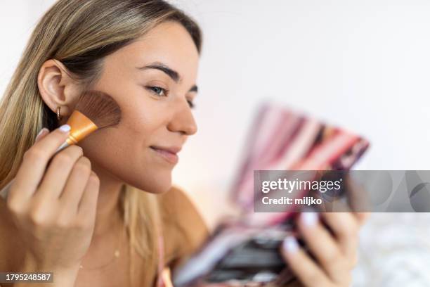 young woman putting on makeup - maquilhagem imagens e fotografias de stock