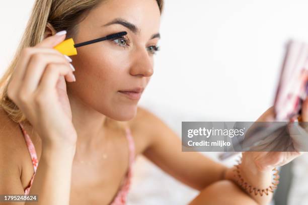 young woman putting on makeup - rímel imagens e fotografias de stock