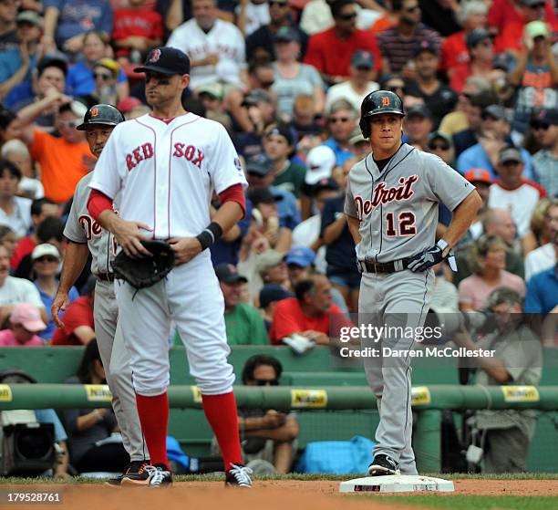 Andy Dirks of the Detroit Tigers stands on third base in the seventh inning as Will Middlebrooks of the Boston Red Sox looks on at Fenway Park on...