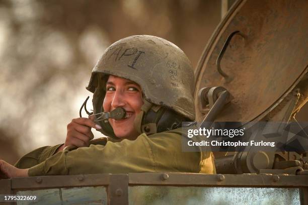 Female Israeli army soldier smiles as she guides her armoured fighting vehicle back to a staging area from the border with Gaza on November 15, 2023...