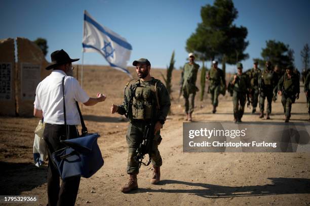 Man gives sweets to Israeli soldiers returning to a staging area from a patrol at the border with Gaza on November 15, 2023 in Southern Israel. More...