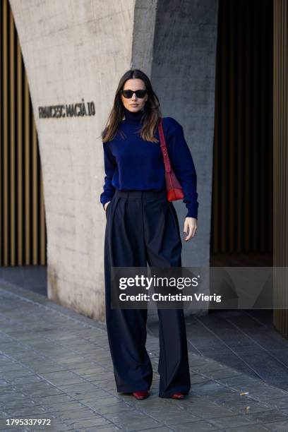 Zina Charkoplia wears black trousers and navy blue sweater Frankie Shop, boots Celine, red bag Elleme, Saint Laurent sunglasses on November 15, 2023...