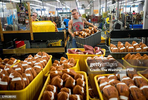 Tyler Gibson carries a tote full of turned, non-inflated footballs to the quality control area to be inspected at the Wilson Football Factory in Ada,...