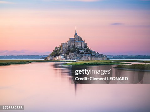 Distant view of the Mont Saint-Michel (Mont-Saint-Michel) reflecting in the sea at sunset during high tide, Manche, Normandie (Normandy), Western France.