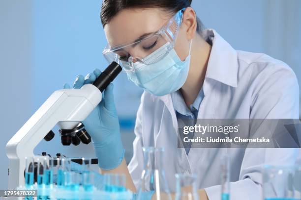 Scientist working with microscope and test tubes in laboratory