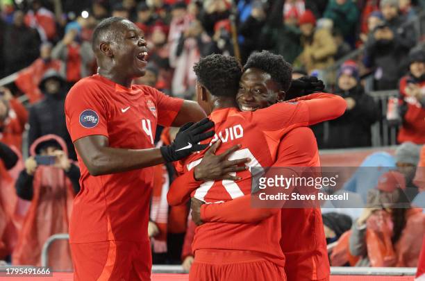 Canada Alphonso Davies celebrates after scoring with Canada forward Jonathan David and a leaping Canada Kamal Miller following as Canada plays...