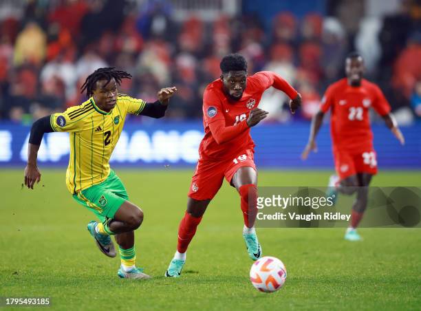 Alphonso Davies of Canada and Dexter Lembikisa of Jamaica chase the ball during a CONCACAF Nations League match at BMO Field on November 21, 2023 in...