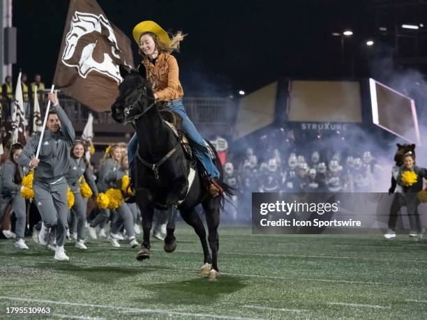 Girl rides a horse to lead the team onto the field before the college football game between the Ball State Cardinals and Western Michigan Broncos on...