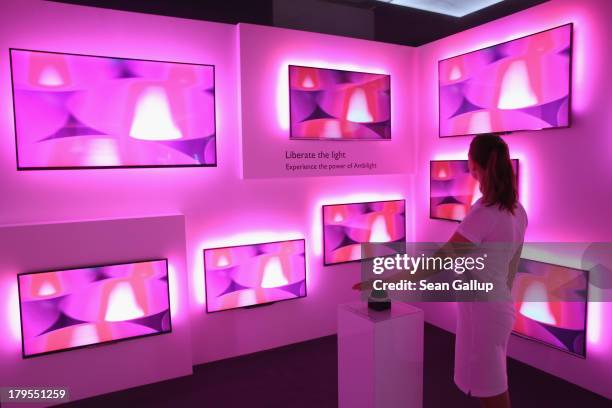 Hostess demonstrates Ambilight televisions on display at the Philips stand at the IFA 2013 consumer electronics trade fair on September 5, 2013 in...