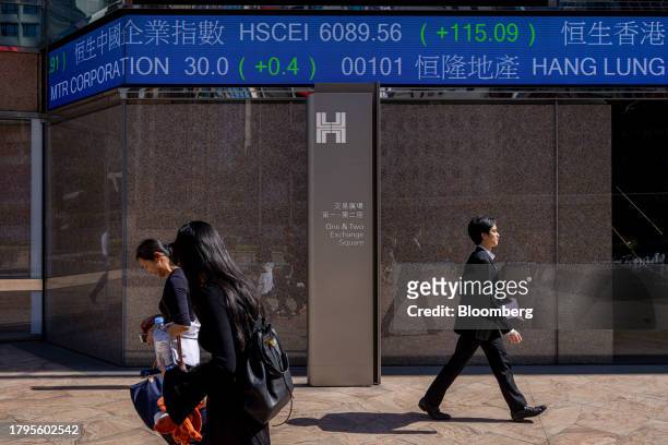 Pedestrians walk past the electronic ticker displaying stock figures at the Exchange Square Complex, which houses the Hong Kong Stock Exchange, in...