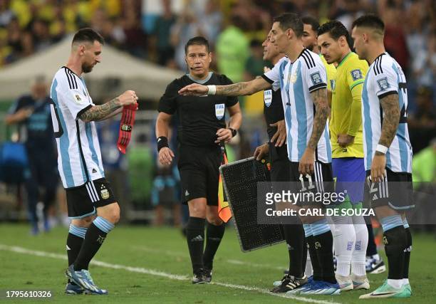 Argentina's forward Lionel Messi gives the captain's band to forward Angel Di Maria before leaving during the 2026 FIFA World Cup South American...