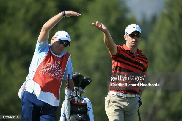 Paul Casey of England and his caddy Dominic Bott signal to the group in front during the first round of the Omega European Masters at the...