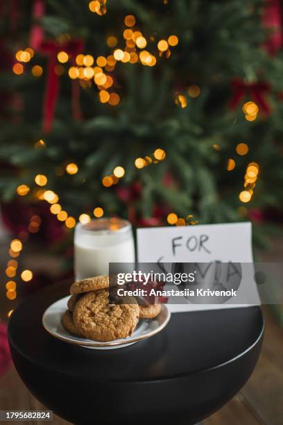 cookies, milk and note to santa claus on table next to christmas tree. - milk letter stock pictures, royalty-free photos & images