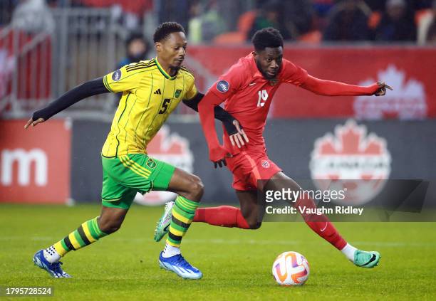 Alphonso Davies of Canada and Ethan Pinnock of Jamaica battle for the ball during a CONCACAF Nations League match at BMO Field on November 21, 2023...