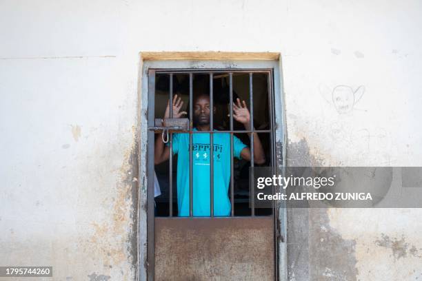 An inmate stands behind a grill in the general prison of Maputo on November 6, 2023. A large pilot of an artificial intelligence programme that has...