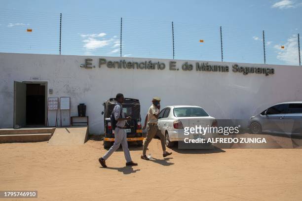 Mozambican Police officer and a man walk outside a maximum security prison in Maputo on November 6, 2023. A large pilot of an artificial intelligence...