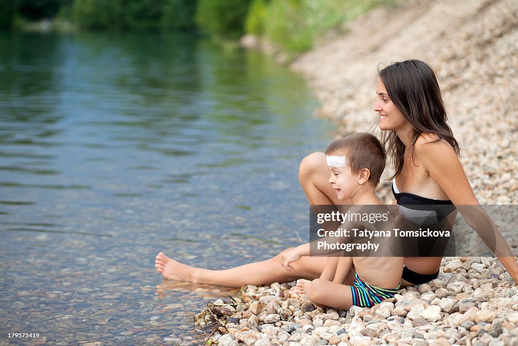 Mom and son, sitting on the shore of a lake