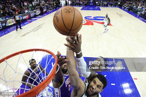 Jayson Tatum of the Boston Celtics shoots a lay up past Joel Embiid and Robert Covington of the Philadelphia 76ers during the fourth quarter at the...