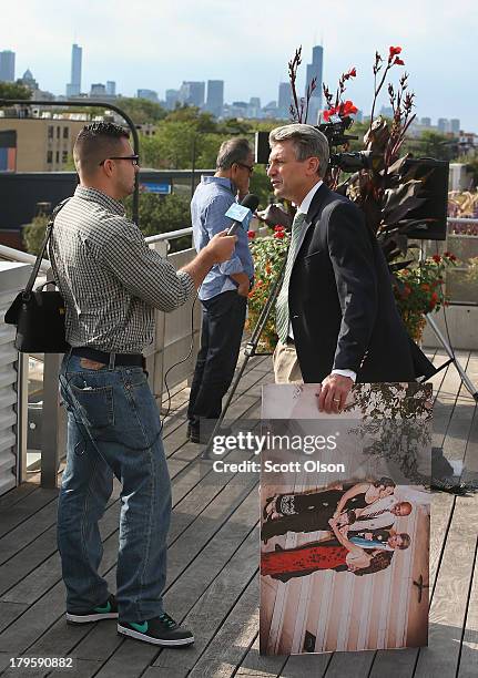 Minneapolis Mayor R.T. Rybak gives an interview while holding a picture taken while he officiated at the marriage of Margaret Miles and Cathy ten...