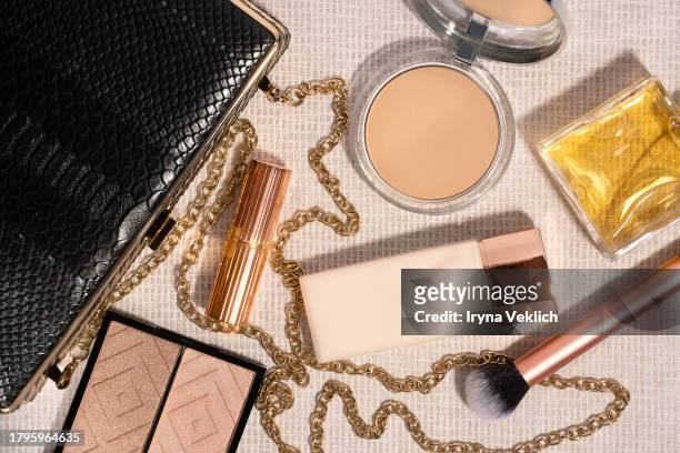 set of black clutch bag and cosmetic make-up products for a woman  on beige colour background. - black purse ストックフォトと画像