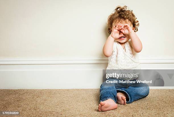 young girl playing peekaboo through her hands. - wainscoting stock pictures, royalty-free photos & images