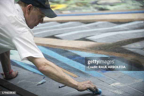 British artist Julian Beever, specialized in pavement drawings, wall murals and realistic paintings, works on his painting in a shopping center in...
