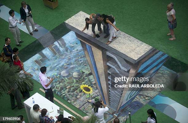 People pose around the work of British artist Julian Beever, specialized in pavement drawings, wall murals and realistic paintings, made in a...