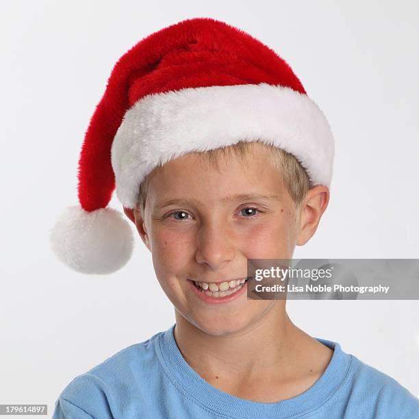 boy with blue eyes wearing santa hat - nikolausmütze stock-fotos und bilder