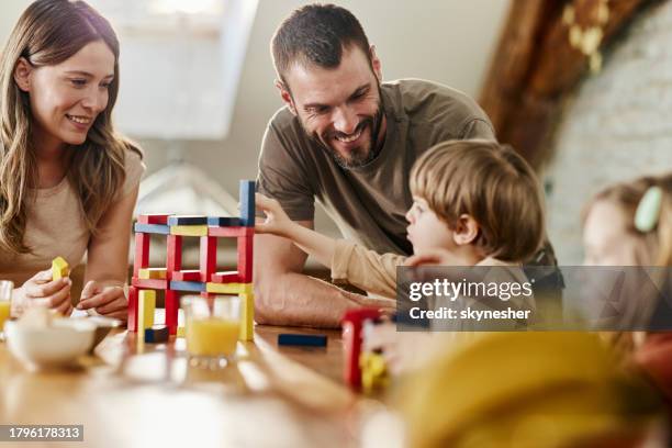 genitori felici e i loro bambini che giocano con i blocchi giocattolo a casa. - giochi foto e immagini stock