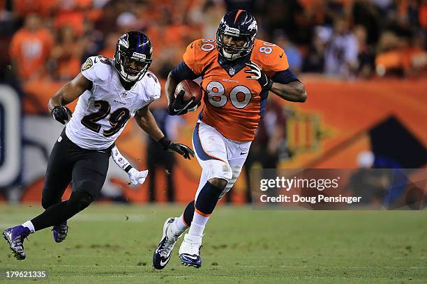 Julius Thomas of the Denver Broncos runs by Michael Huff of the Baltimore Ravens before running in for a 24-yard touchdown in the second quarter...