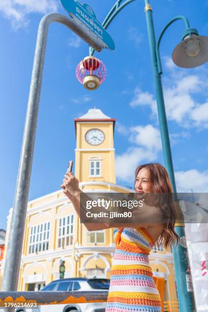 phuket adventure, gen z asian woman captures phuket oldtown's charm with smartphone during travel. - historische wijk stockfoto's en -beelden