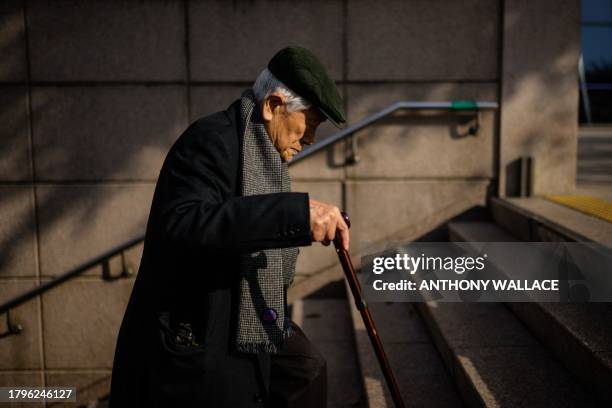 An elderly man uses his walking stick while climbing stairs leading out from an underground metro station in Seoul on November 22, 2023.