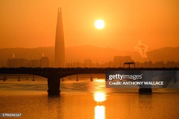 General view shows the Lotte Tower and the sun rising over the Han river in Seoul on November 22, 2023.