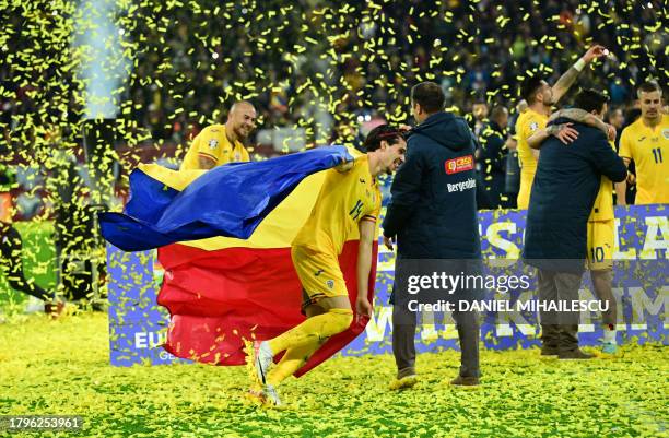 Romania's midfielder Ianis Hagi celebrates with the Romanian flag at the end of the UEFA Euro 2024 group I qualification football match between...