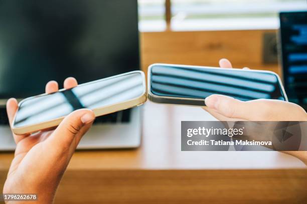 two phones in women’s hands transmit data to each other via bluetooth. close-up. - bluetooth photos et images de collection
