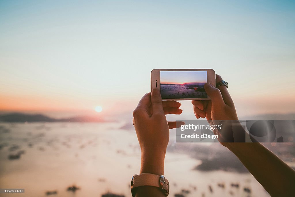 Taking photo of beautiful sunset with smartphone