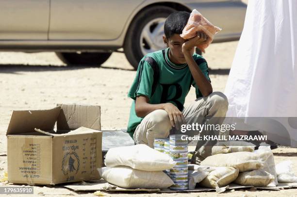 Young Syrian refugee boy sells canned tuna and other food items in the Zaatari refugee camp, located close to the Jordanian city of Mafraq, near the...