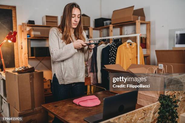 a woman is photographing a pink hat to post a new item on her online shop - photographing clothes stock pictures, royalty-free photos & images