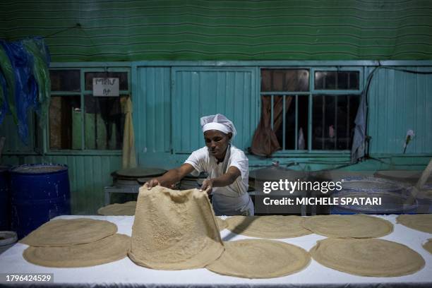 Woman prepares injera, a sour fermented flatbread with a slightly spongy texture that is Ethiopia's staple food, in a bakery in Addis Ababa on...