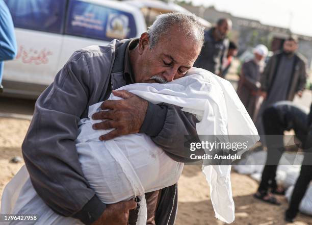 Man hugs the lifeless body of a child as the Palestinians killed in Israeli attacks are taken out of the mortuary of Al-Aqsa Martyr's Hospital for...