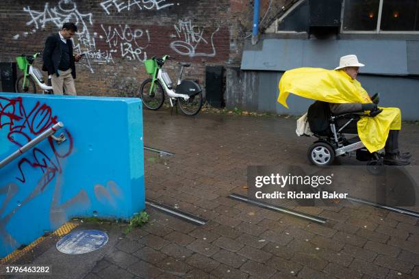 An elderly man rides a mobility scooter along the pavement in Waterloo SE1, on 21st November 2023, in London, England.