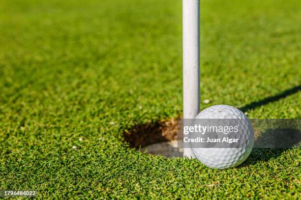 golf ball by the hole - abschlagen stock-fotos und bilder