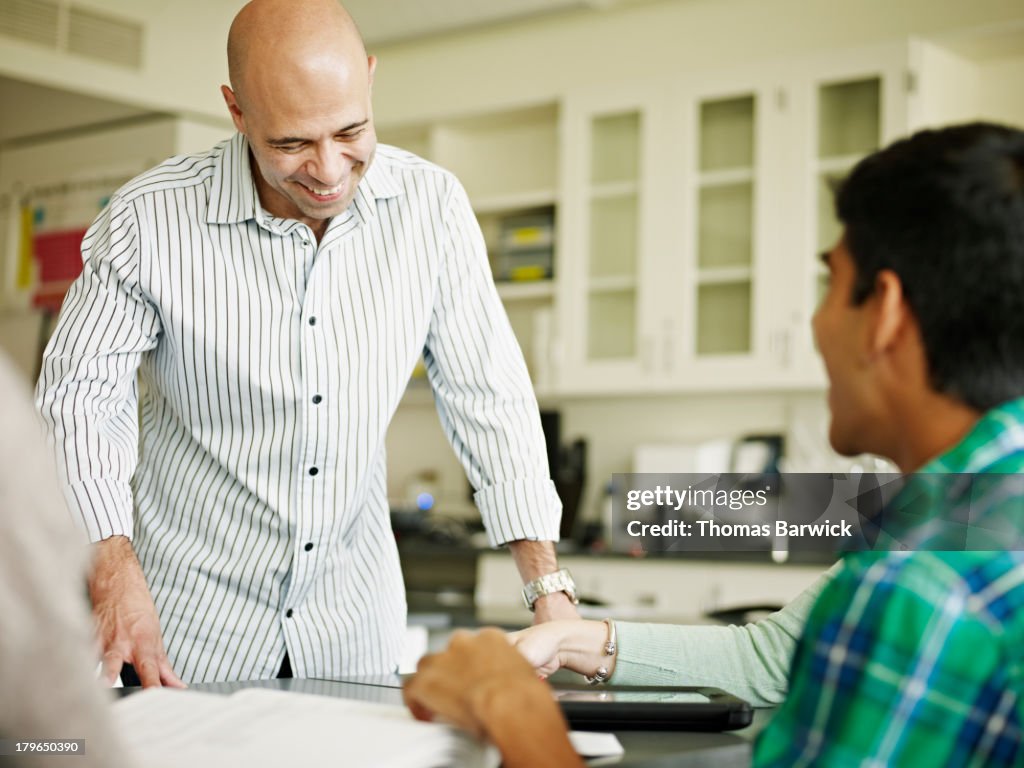 Male teacher in classroom helping students