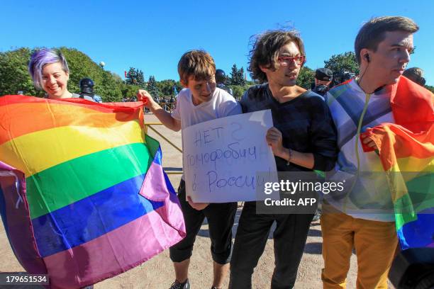 Gay rights activist holds rainbow flags and posters as they take part in a gay pride event in Saint Petersburg on September 6, 2013. The poster...