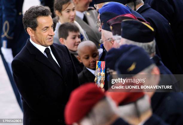 France's President Nicolas Sarkozy shakes hands with veterans in front of the tomb of the Unknown soldier at the Arc de Triomphe in Paris on November...