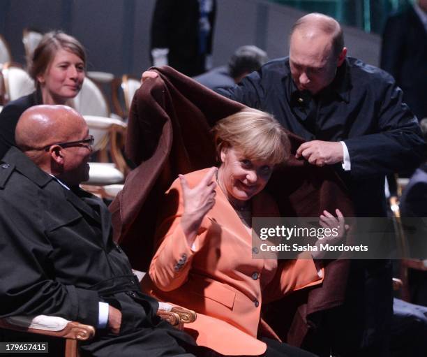 President of the Russian Federation Vladimir Putin, helps Chancellor of Germany Angela Merkel with a coat as President of South Africa Jacob Zuma...