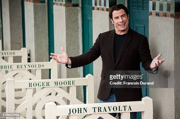 John Travolta poses next to the beach closet dedicated to him during a photocall on the Promenade des Planches during the 39th Deauville American...