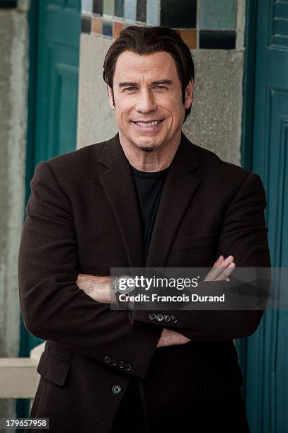 John Travolta poses next to the beach closet dedicated to him during a photocall on the Promenade des Planches during the 39th Deauville American...