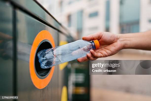 young man recycling a water bottle in malmo in sweden - bottle bank stock pictures, royalty-free photos & images