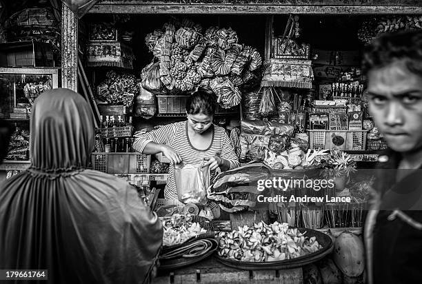 Shopkeeper serves customers at the busy Pasar Badung market, Denpasar, Indonesia.